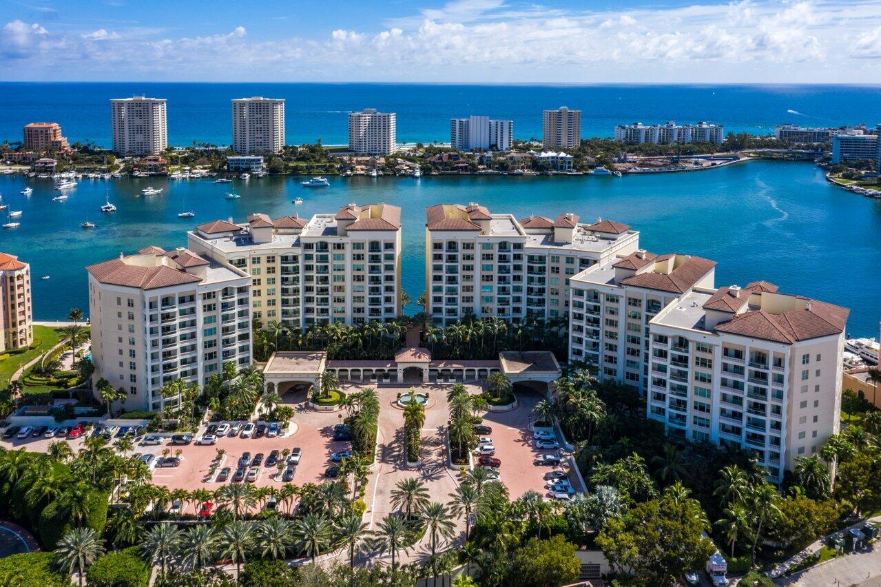Waterfront condominium complex beside a marina, with the ocean and coastal high-rises beyond.